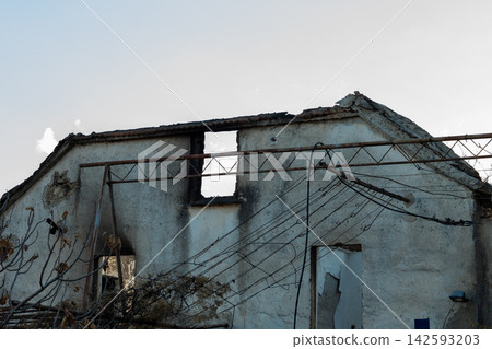 Dilapidated abandoned house with collapsed roof and tangled overhead wires Dilapidated abandoned house with collapsed roof and tangled overhead wires 142593203
