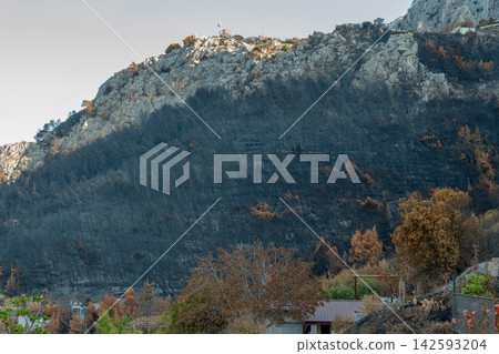 Burned mountain slope above small village in Croatia under clear sky Burned mountain slope above small village in Croatia under clear sky 142593204