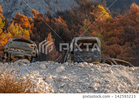 Burned abandoned vehicles on rocky hillside after wildfire damage Burned abandoned vehicles on rocky hillside after wildfire damage 142593213