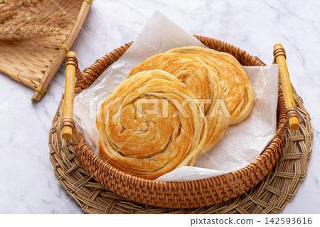 traditional Chinese Pansi Shaobing, crispy spiral layered sesame flatbread pancake served on a vintage plate. traditional Chinese Pansi Shaobing, crispy spiral layered sesame flatbread pancake served on a vintage plate. 142593616