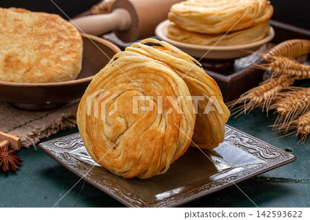 traditional Chinese Pansi Shaobing, crispy spiral layered sesame flatbread pancake served on a vintage plate. traditional Chinese Pansi Shaobing, crispy spiral layered sesame flatbread pancake served on a vintage plate. 142593622