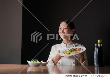 A female chef holding a delicious-looking plate. A female chef holding a delicious-looking plate. 142593652