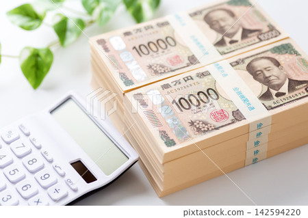 一疊1000萬日元鈔票和一個白色計算器 一疊1000萬日元鈔票和一個白色計算器 142594220