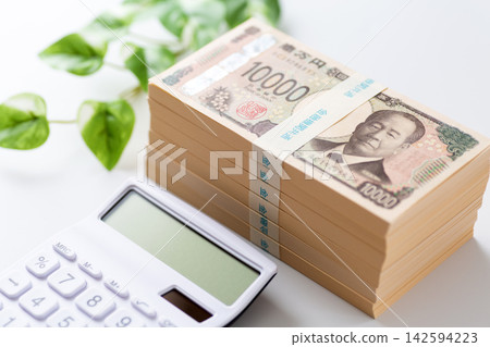 一疊600萬日元鈔票和一個白色計算器 一疊600萬日元鈔票和一個白色計算器 142594223