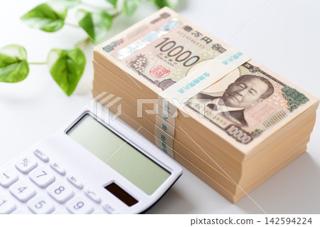 一疊500萬日圓鈔票和一台白色計算器 一疊500萬日圓鈔票和一台白色計算器 142594224