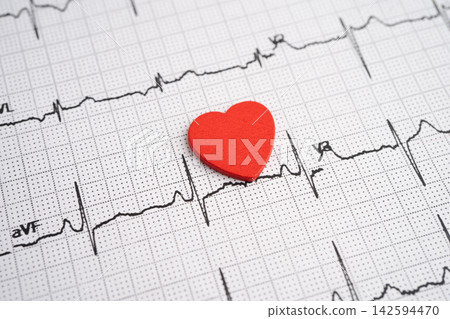 Red heart on electrocardiogram ECG with red heart, heart wave, heart attack, cardiogram report. Red heart on electrocardiogram ECG with red heart, heart wave, heart attack, cardiogram report. 142594470
