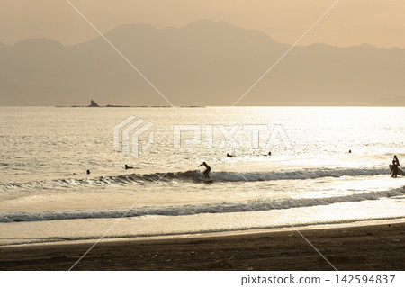 Shonan Kugenuma Beach: The shimmering surface of the sea and the silhouettes of surfers in the setting sun. Shonan Kugenuma Beach: The shimmering surface of the sea and the silhouettes of surfers in the setting sun. 142594837