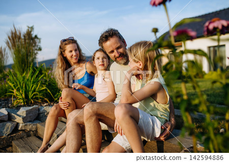 Happy young family spending summer evening together outside their new home. Happy young family spending summer evening together outside their new home. 142594886