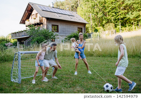 Family playing soccer together in backyard during summer. Family playing soccer together in backyard during summer. 142594979