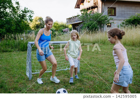 Mom and kids playing football in backyard during summer afternoon. Mom and kids playing football in backyard during summer afternoon. 142595005