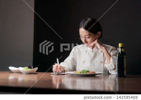 一位不斷研發新食譜的女廚師。 一位不斷研發新食譜的女廚師。 142595408