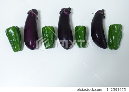 A food photograph of summer vegetables, bell peppers and eggplants, taken in a vertical composition against a white background. A food photograph of summer vegetables, bell peppers and eggplants, taken in a vertical composition against a white background. 142595655