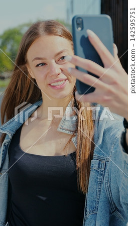 Vertical video. Young woman blogger captures city life on mobile camera for vlog. Vertical video. Young woman blogger captures city life on mobile camera for vlog. 142595751