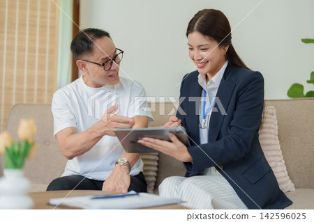 Asian financial advisor explaining digital insurance policy to senior man on tablet 142596025