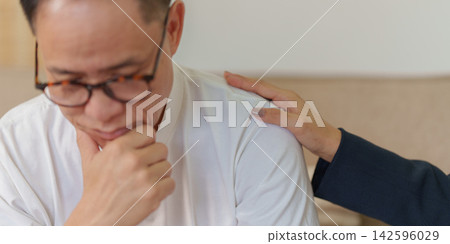 Supportive hand comforting worried senior Asian man during counseling session Supportive hand comforting worried senior Asian man during counseling session 142596029