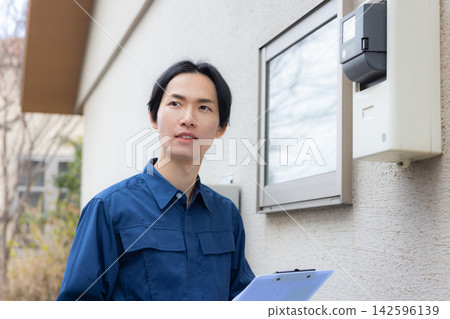 一名身穿工作服的男子正在檢查住宅設備。 一名身穿工作服的男子正在檢查住宅設備。 142596139