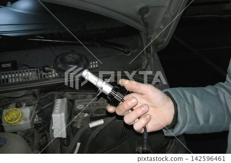 Xenon lamp in hands of an electrician. Replacing xenon lamps. Xenon lamp in hands of an electrician. Replacing xenon lamps. 142596461