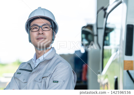 A smiling on-site engineer stands in front of heavy machinery. A smiling on-site engineer stands in front of heavy machinery. 142596536