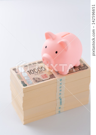 一疊1000萬日元鈔票和一個粉紅色的小豬存錢罐 一疊1000萬日元鈔票和一個粉紅色的小豬存錢罐 142596651