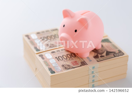 一疊1000萬日元鈔票和一個粉紅色的小豬存錢罐 一疊1000萬日元鈔票和一個粉紅色的小豬存錢罐 142596652