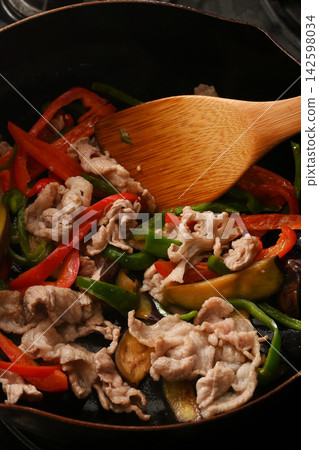 Eggplant, green peppers and pork being fried in a frying pan Eggplant, green peppers and pork being fried in a frying pan 142598034