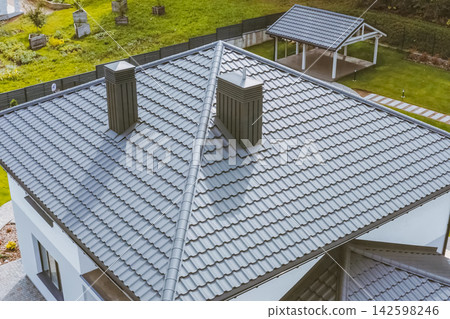 House with a gray metal roof. Corrugated metal roof and metal roofing. Modern roof made of metal. House with a gray metal roof. Corrugated metal roof and metal roofing. Modern roof made of metal. 142598246