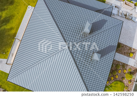 House with a gray metal roof. Corrugated metal roof and metal roofing. Modern roof made of metal. House with a gray metal roof. Corrugated metal roof and metal roofing. Modern roof made of metal. 142598250