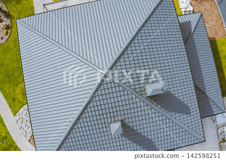 House with a gray metal roof. Corrugated metal roof and metal roofing. Modern roof made of metal. 142598251