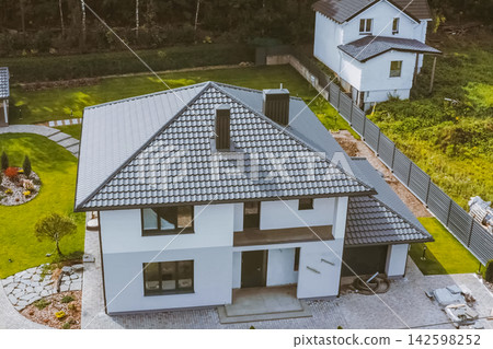 House with a gray metal roof. Corrugated metal roof and metal roofing. Modern roof made of metal. House with a gray metal roof. Corrugated metal roof and metal roofing. Modern roof made of metal. 142598252