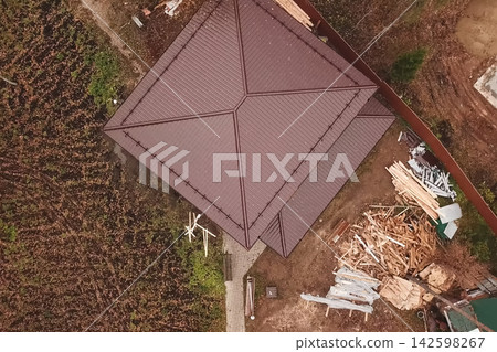House with a brown metal roof.Corrugated metal roof and metal roofing. Modern roof made of metal. House with a brown metal roof.Corrugated metal roof and metal roofing. Modern roof made of metal. 142598267
