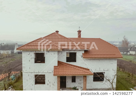 House with an orange metal roof. Corrugated metal roof and metal roofing. Modern roof made of metal. 142598277