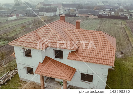 House with an orange metal roof. Corrugated metal roof and metal roofing. Modern roof made of metal. House with an orange metal roof. Corrugated metal roof and metal roofing. Modern roof made of metal. 142598280