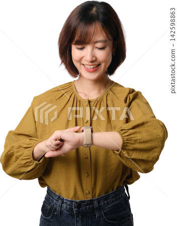 Smiling Asian woman checking smartwatch on her wrist while wearing mustard blouse and standing against transparent background Smiling Asian woman checking smartwatch on her wrist while wearing mustard blouse and standing against transparent background 142598863