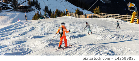 Teenager kid girl skier skiing fast downhill winter alpine skiing resort. Female sporty child person with backpack cat like mountain Alps snow slope outdoors cold snowy sunny backlit light day Teenager kid girl skier skiing fast downhill winter alpine skiing resort. Female sporty child person with backpack cat like mountain Alps snow slope outdoors cold snowy sunny backlit light day 142599853