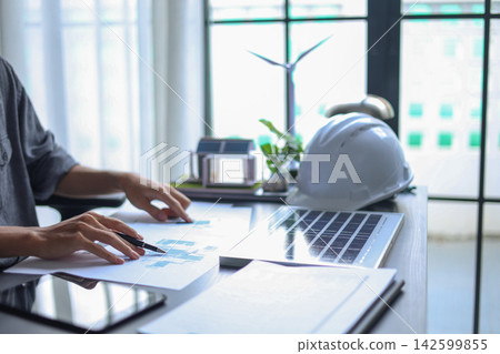 Professional Engineer Planning Sustainable Solar Energy Installation with Blueprints in office. Professional Engineer Planning Sustainable Solar Energy Installation with Blueprints in office. 142599855