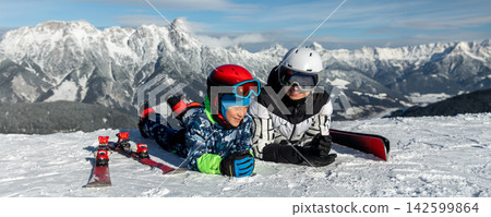 Mother child enjoy relax lying snowy slope alpine resort smiling have fun skiing mountain panoramic background. Bright winter suns alpine panorama joyful family healthy sport vacation mood Mother child enjoy relax lying snowy slope alpine resort smiling have fun skiing mountain panoramic background. Bright winter suns alpine panorama joyful family healthy sport vacation mood 142599864