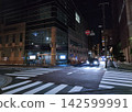 A traffic lightless intersection at night where cars are stopped. 142599991
