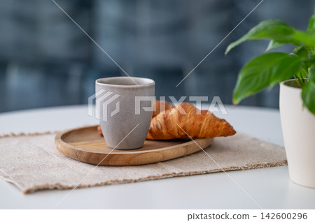 Coffee and Croissant on a Minimalist Table with Green Plant Coffee and Croissant on a Minimalist Table with Green Plant 142600296