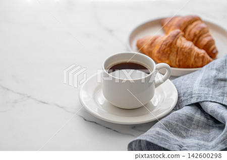 Cup of freshly espresso coffee and fresh croissants on a marble background Cup of freshly espresso coffee and fresh croissants on a marble background 142600298