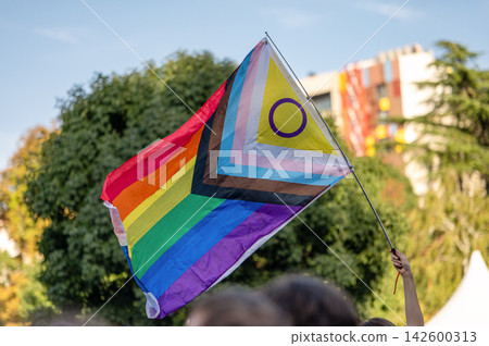 Rainbow Pride Flag with Intersex Symbol Against Blue Sky Rainbow Pride Flag with Intersex Symbol Against Blue Sky 142600313
