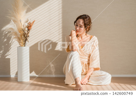 A woman lost in thought in the soft sunlight. A natural portrait with a striking, melancholic expression. 142600749