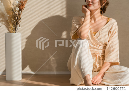 一位身穿自然米色套裝的女士正在放鬆休息。這種休閒時尚在自然光下熠熠生輝。 一位身穿自然米色套裝的女士正在放鬆休息。這種休閒時尚在自然光下熠熠生輝。 142600751