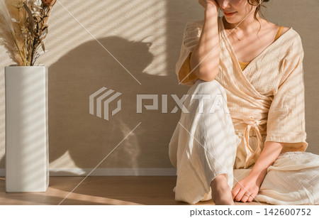 A woman relaxing in a natural beige outfit. Relaxed fashion that shines in natural light. A woman relaxing in a natural beige outfit. Relaxed fashion that shines in natural light. 142600752