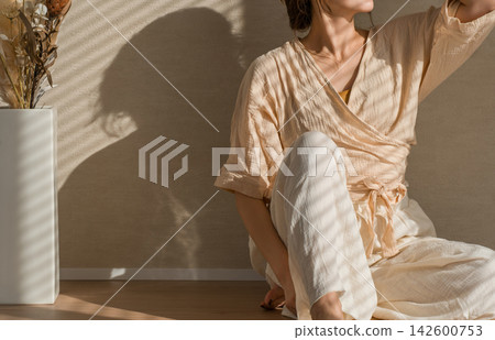一位身穿自然米色套裝的女士正在放鬆休息。這種休閒時尚在自然光下熠熠生輝。 一位身穿自然米色套裝的女士正在放鬆休息。這種休閒時尚在自然光下熠熠生輝。 142600753