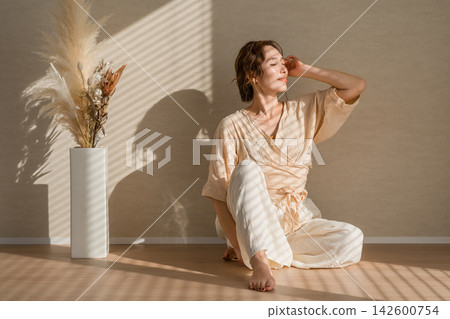 一位女士在陽光明媚的家中放鬆身心。這是一棟客製化建造的房屋,內部裝潢自然,自然光線充足。 一位女士在陽光明媚的家中放鬆身心。這是一棟客製化建造的房屋,內部裝潢自然,自然光線充足。 142600754