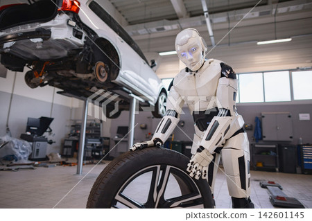 A humanoid robot is shown in a garage, holding a car tire next to a vehicle being serviced on a lift A humanoid robot is shown in a garage, holding a car tire next to a vehicle being serviced on a lift 142601145