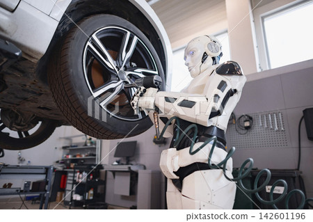 A humanoid robot is actively engaged in changing a car tire in a workshop setting, utilizing a pneumatic wrench A humanoid robot is actively engaged in changing a car tire in a workshop setting, utilizing a pneumatic wrench 142601196
