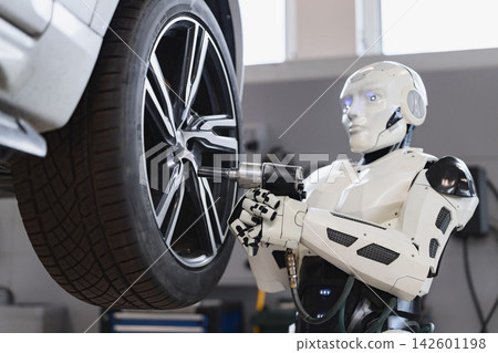 A humanoid robot uses a power tool to tighten the lug nuts on a car's wheel in a workshop setting A humanoid robot uses a power tool to tighten the lug nuts on a car's wheel in a workshop setting 142601198