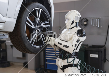A humanoid robot is using a power tool to tighten the lug nuts on a car's wheel in a workshop setting A humanoid robot is using a power tool to tighten the lug nuts on a car's wheel in a workshop setting 142601201