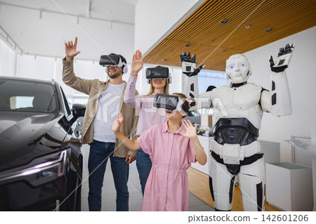 A family and a humanoid robot experience virtual reality headsets together in a modern car dealership setting 142601206